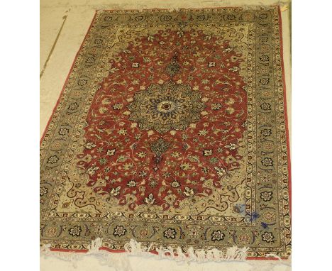 A Persian style carpet, the central panel set with a stylised flower burst medallion on a pink ground with all over floral de