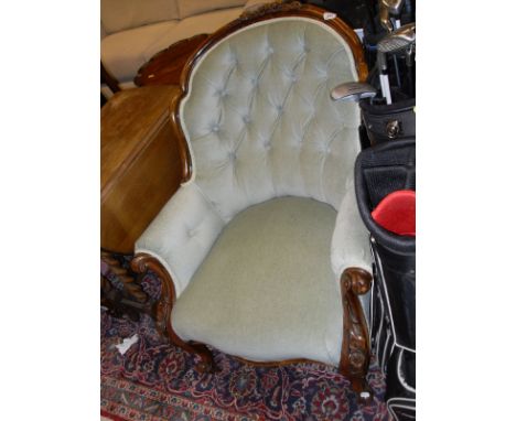 A Victorian walnut framed button backed salon chair with carved decoration raised on scroll front support to castors, the uph