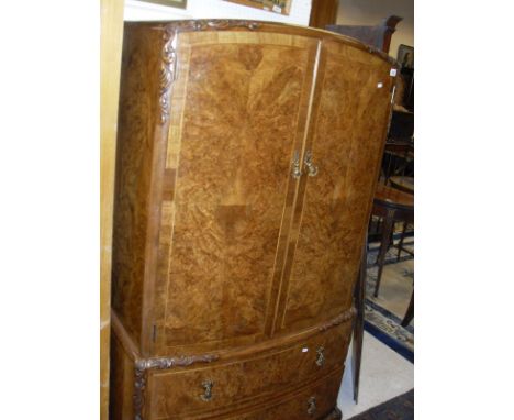 A 1930's burr walnut and cross banded and herringbone strung bow fronted linen press with acanthus carved and flowerhead deco