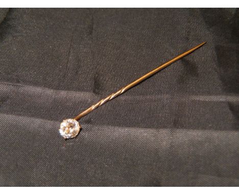 A yellow metal mounted stick pin with single diamond in a claw setting approx .0.5 carat