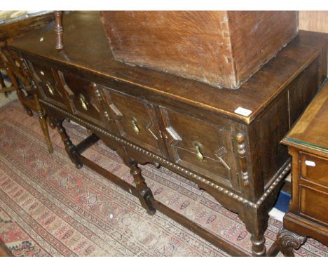 An oak dresser in the 17th Century style with applied moulded decoration, the plain top above a single drawer and pair of cup