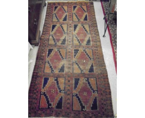 A Beluch style rug, the central panel set with eight repeating square medallions on a burgundy ground within a stepped burgun