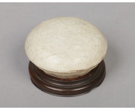 A Chinese circular paste pot and cover on associated hardwood base. With raised scroll mouldings and with white crackle glaze