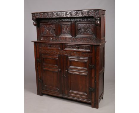 A William and Mary period oak court cupboard. The frieze is carved with trailing vines, inscribed R. S. G and dated 1700. The