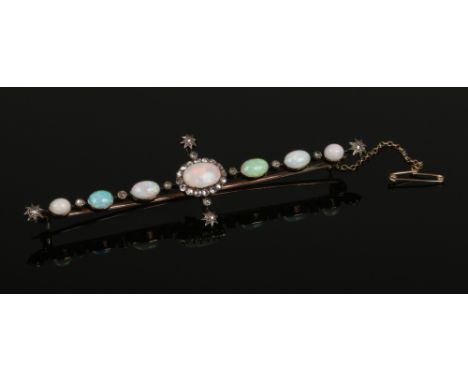 A Victorian yellow metal cruciform bar brooch. Set with seven mixed ovoid opals interspersed with rose cut diamonds, the larg