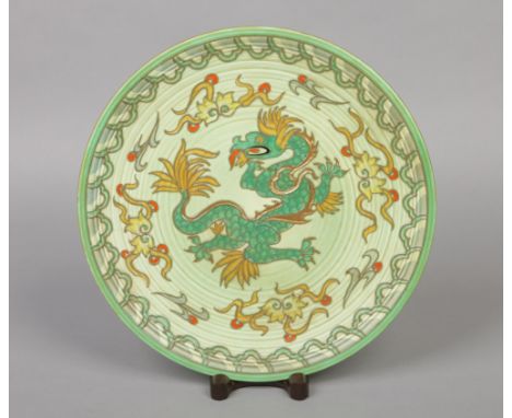 A Crown Ducal pottery wall charger designed by Charlotte Rhead. Tube lined over a green ground with a dragon. Printed mark an