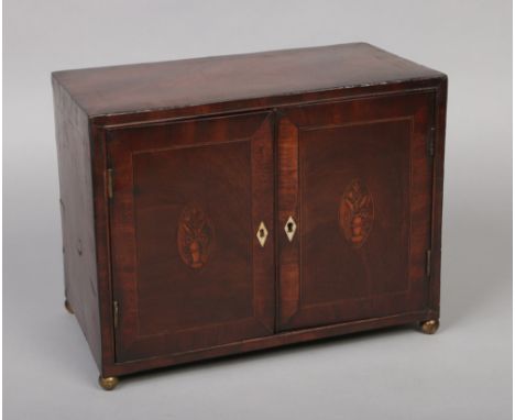 A Georgian mahogany table cabinet, crossbanded, with strung inlay, patera and raised on brass ball feet. Opening to reveal a 
