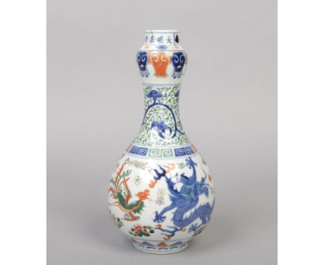 A Chinese Wucai glazed gourd shaped bottle vase. Decorated with a pair of dragons and phoenix under a key fret and lotus scro