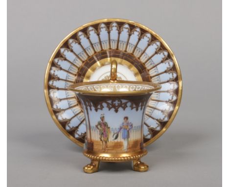 A French Empire Darte Freres porcelain three footed cabinet cup and saucer. Painted with a continuing landscape with a soldie