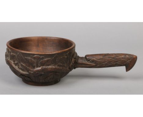 An early 20th century Continental folk art carved wooden ladle. The handle is formed as a stylized eagle head, the bowl has a