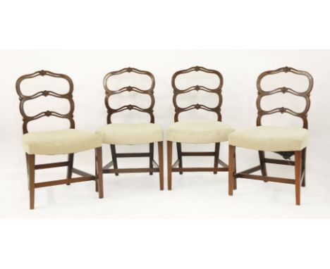 A set of four George III mahogany dining chairs,with pierced wavy ladder backs and overstuffed seats, on square tapering fron