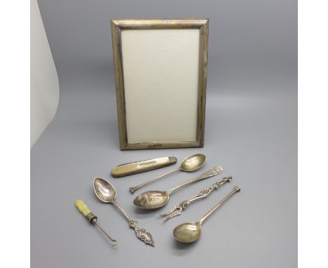A silver and mother of pearl penknife, three silver spoons, one other spoon, a silver photograph frame, a button hook and an 
