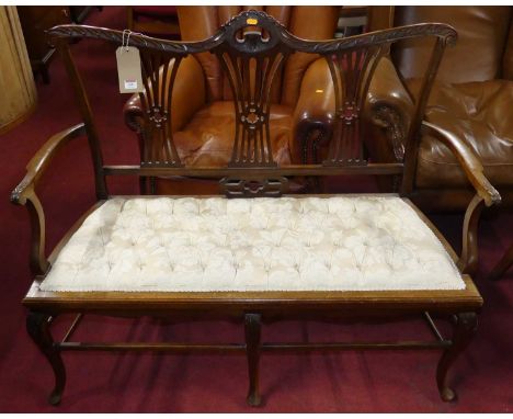 An Edwardian mahogany splat back two-seater salon settee, with carved floral detail and cream silk damask buttoned upholstere