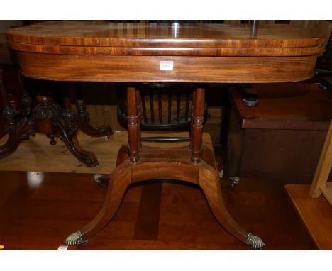 A Regency mahogany D-shaped fold-over baize lined card table, having a swivel top, raised on ring turned supports to brass ca