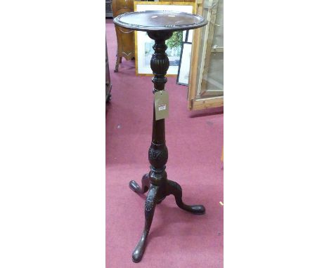An early 20th century mahogany circular fixed top pedestal tripod plant stand, raised on turned floral carved and fluted colu