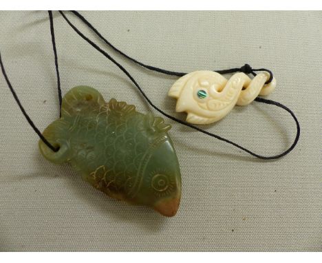 AN ANTIQUE CARVED JADE FISH FORM PENDANT, TOGETHER WITH A LATER SOUTH SEA PENDANT. 