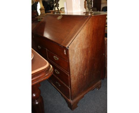 A George III oak bureau with fall enclosing a fitted interior with well, small drawers and pigeon holes, above two short over