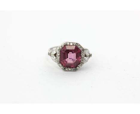 A pink sapphire and diamond ring, the octagonal step cut stone within a border of eight cut diamonds and with navette diamond