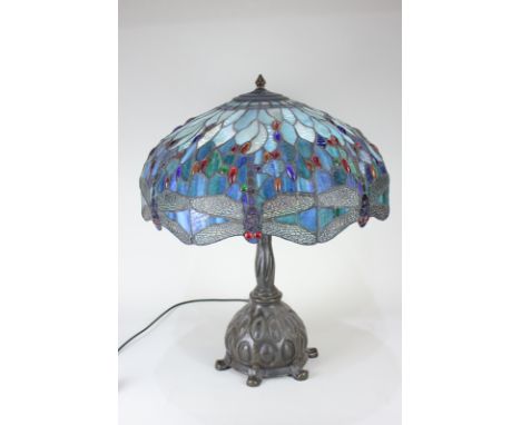 A Tiffany style lead glass table lamp, the domed shade with dragonflies against a blue background, over a naturalistic base, 