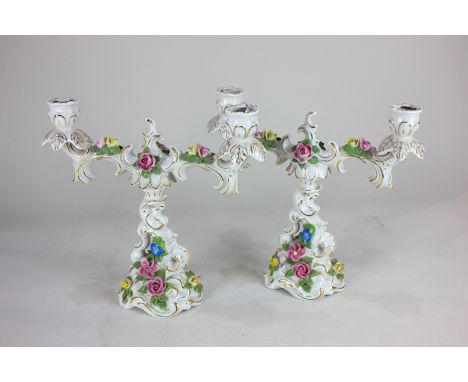 A pair of Dresden porcelain candelabra, each with two-branch light holders, with floral and gilt embellishments on white grou