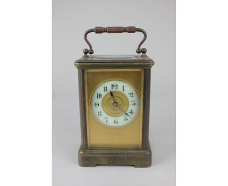 A brass and bevelled glass cased carriage clock, the circular enamel dial with Arabic numerals within gilt surround, marked M