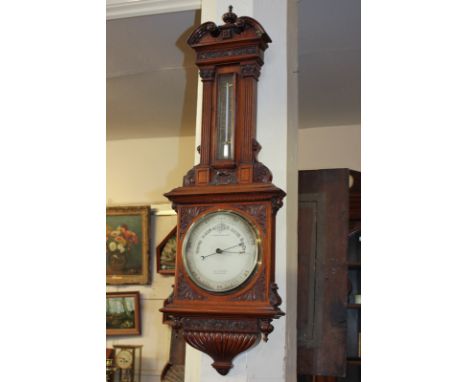 A Victorian mahogany cased wall barometer and thermometer by T. Armstrong & Bro, the case carved with floral scrolling design