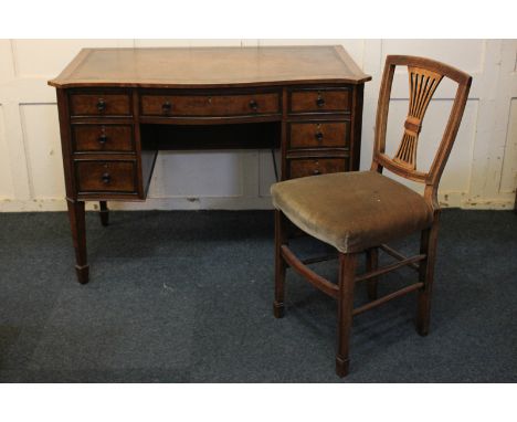 An Edwardian inlaid mahogany kneehole desk, the leather inset serpentine top with canted corners, above an arrangement of sev