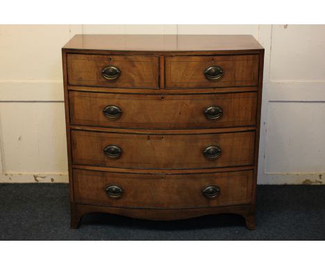 A Maple & Co. crossbanded mahogany bow-front chest of two short over three long drawers, with ebony line inlay and brass oval