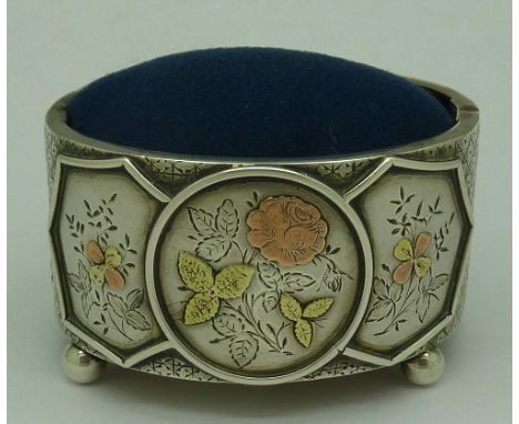 A pin cushion formed from a Victorian silver bangle with applied gold decoration