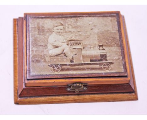 A treen needle box having a transfer print of a boy riding a model engine and velvet fitted interior, length 13.5cm. Conditio