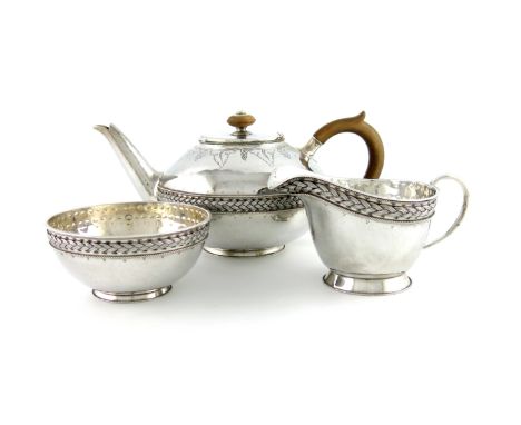 A three-piece Arts and Crafts silver tea set, by William H Haseler, Birmingham 1911, circular form, spot-hammered decoration,