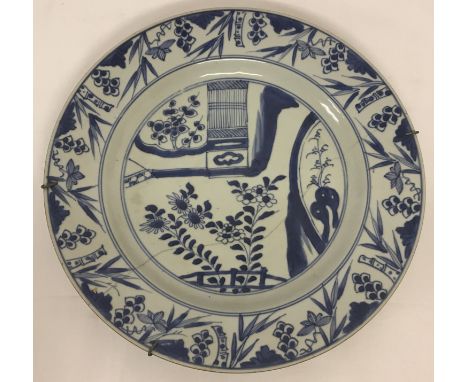 A vintage Chinese blue and white hand painted ceramic plate.  With bamboo decoration to rim and aged staple repair to reverse
