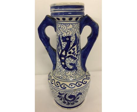 An oriental ceramic blue and white 2 handled urn.  With hand painted mythical creature design to neck. Slight damage to handl