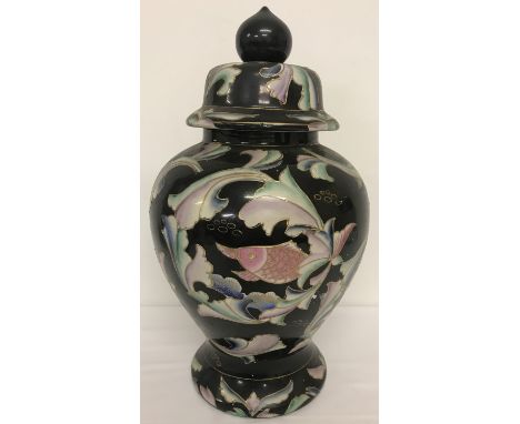 An oriental ceramic lidded temple jar with hand painted koi carp decoration and gilded detail.  Black ground with green, pink