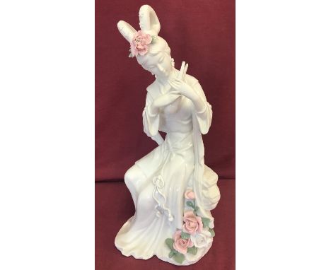 A modern Blanc de Chine ceramic figurine of a geisha playing a musical instrument. With pink flower detail. Approx. 41cm tall