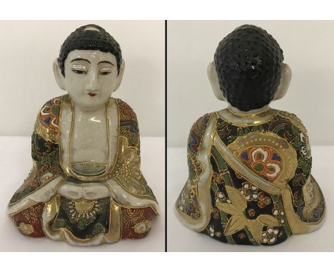 A ceramic sitting Buddha figure with gilt and hand painted floral decoration to his robe.   Approx. 13cm tall.