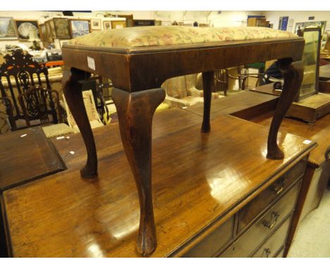 An 18th Century walnut dressing stool, the upholstered drop-in seat within a moulded frame on cabriole legs to hoof feet