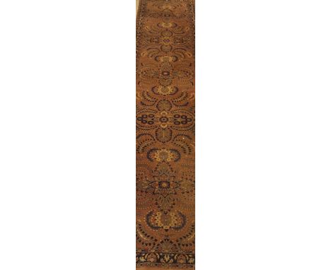 A Persian runner, the central panel set with repeating floral sprays on a pink background, 405 cm x 80 cm CONDITION REPORTS O