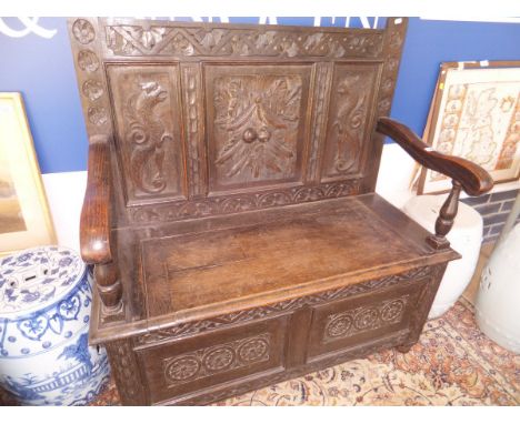 A carved oak bench with panelled back and lift top seat CONDITION REPORTS Has general wear and tear conducive with age and us