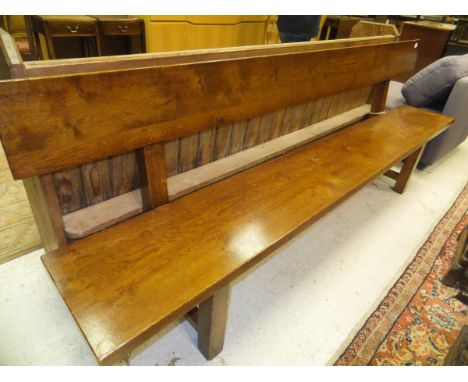 An oak bench of plank form on square supports united by a centre stretcher