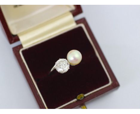 A mid 20th century diamond and untested pearl ‘toi et moi’ the transitional diamond set in white metal claw setting edge, wit
