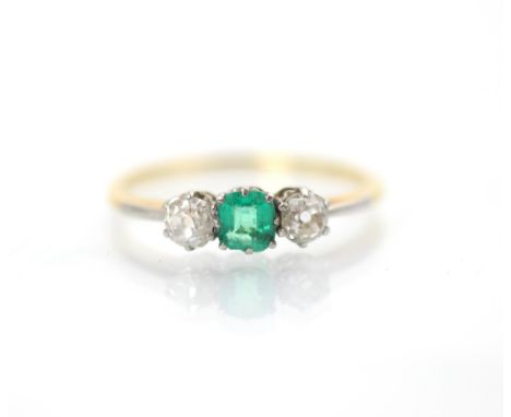 An early 20th century emerald and diamond three stone ring, the central square cut emerald with an old cut diamond to each si