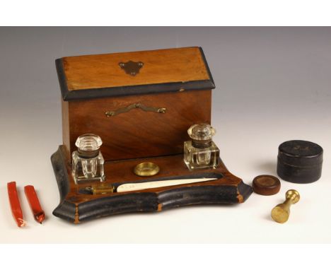 A Victorian desk stand, late 19th century, comprising a mahogany stationery box with hinged cover set to a shaped mahogany ba