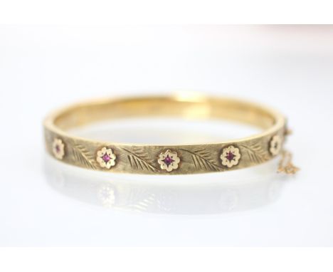 A Cropp and Farr 9ct yellow gold bangle, the hollow bangle set with five synthetic rubies within flower head designed motif w