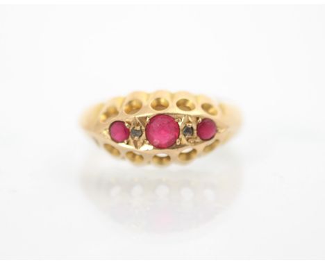 An early 20th century 18ct yellow gold untested ruby ring, the three graduated red stones with a diamond chip between stones,