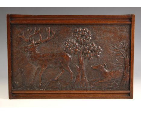 A Folk Art relief carved walnut hunting scene panel, 19th century, depicting a stag and hound within a tree lined landscape, 