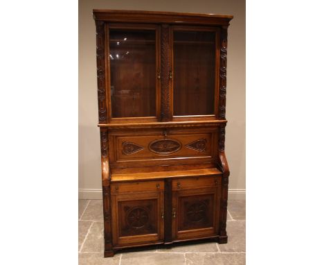 A carved golden oak secretaire bookcase, late 19th century, probably Welsh, the moulded cornice over a pair of glazed doors o