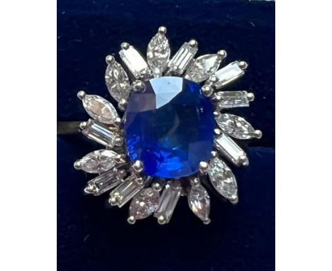 A 1960's sapphire and diamond cluster ring, the central cushion cut sapphire within white metal claw setting, surround by eig