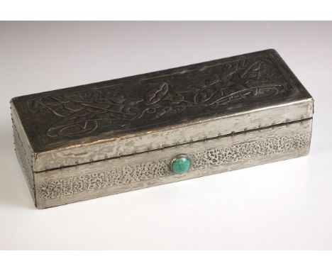 An Art Nouveau pewter covered glove box, the hinged cover embossed with stylised foliage, above an inset green cabochon to th