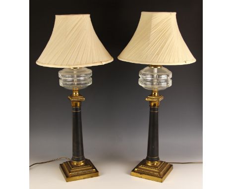 A pair of Victorian brass column oil lamps, later converted, each with a glass reservoir upon a brass capital, painted column